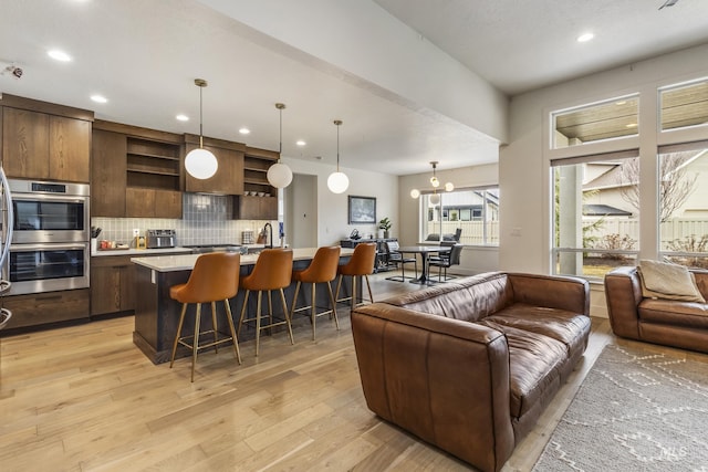 kitchen with tasteful backsplash, a breakfast bar area, open floor plan, stainless steel double oven, and open shelves