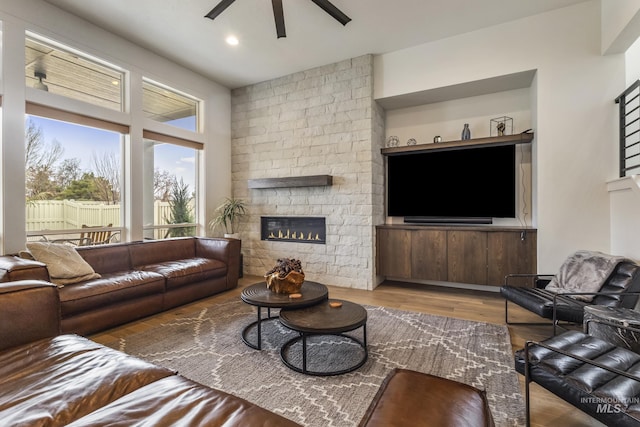 living room featuring ceiling fan, a fireplace, wood finished floors, and recessed lighting