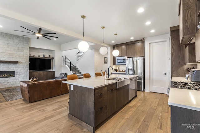 kitchen featuring appliances with stainless steel finishes, light countertops, light wood-style floors, and dark brown cabinets