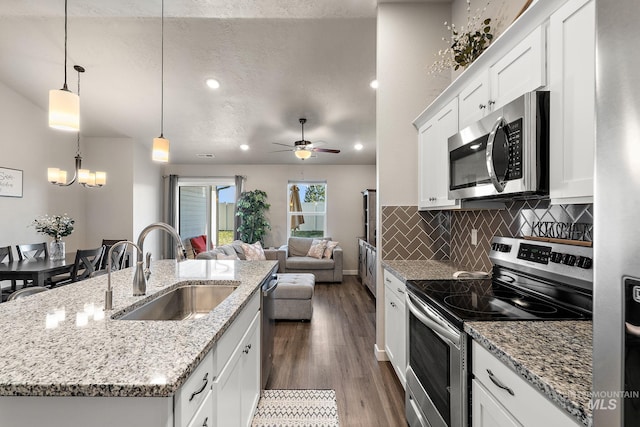 kitchen featuring appliances with stainless steel finishes, pendant lighting, white cabinetry, an island with sink, and sink