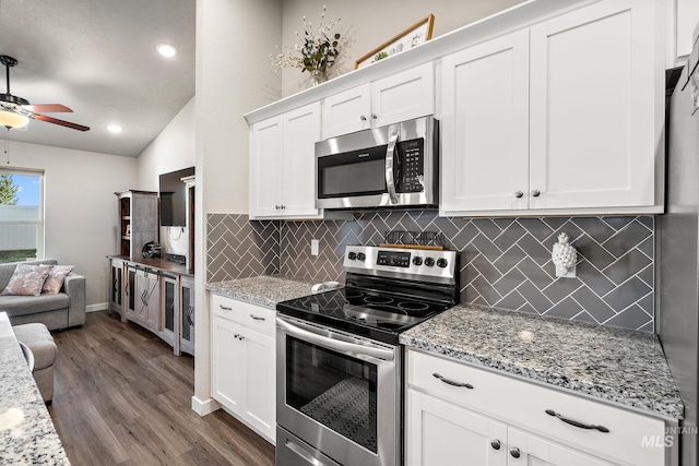 kitchen with light stone counters, stainless steel appliances, dark hardwood / wood-style floors, and white cabinets