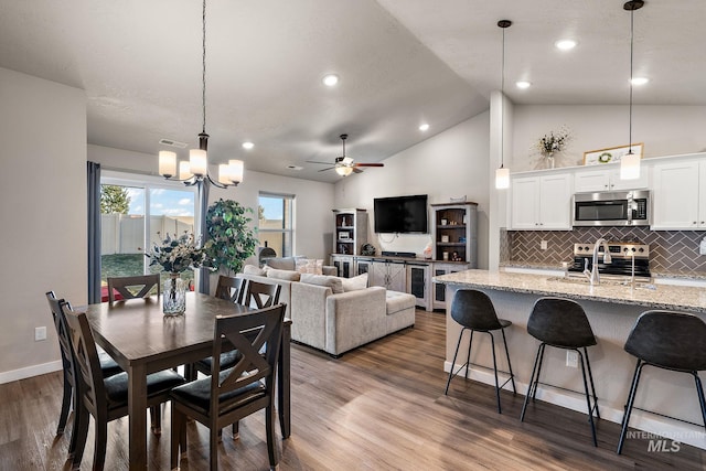 dining room featuring ceiling fan, lofted ceiling, wood-type flooring, and sink