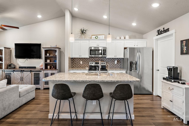 kitchen with appliances with stainless steel finishes, decorative light fixtures, sink, white cabinets, and a center island with sink