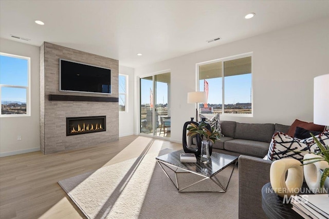 living room featuring recessed lighting, visible vents, wood finished floors, and a fireplace