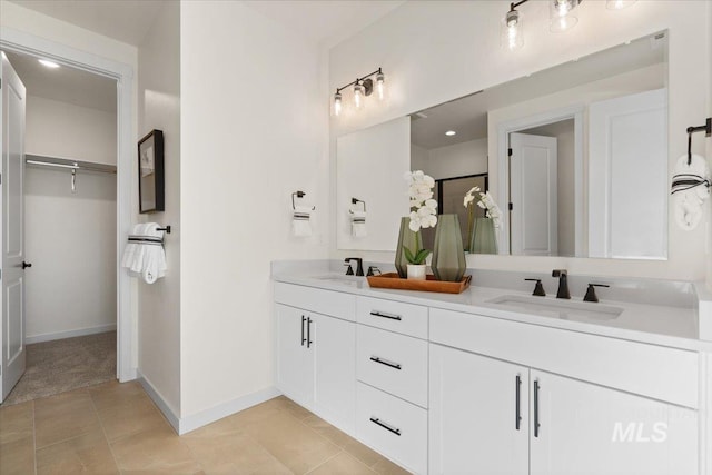 bathroom with double vanity, tile patterned floors, baseboards, and a sink