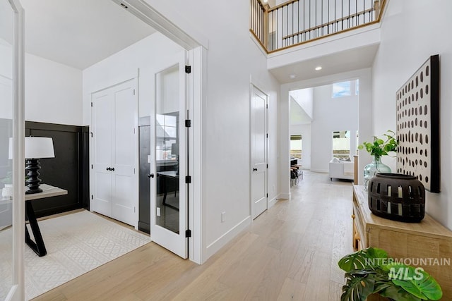 corridor with light hardwood / wood-style flooring and a high ceiling