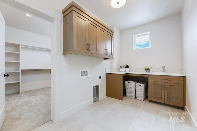 clothes washing area with sink, washer hookup, light carpet, electric dryer hookup, and cabinets