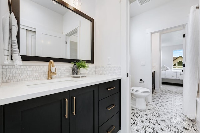 bathroom featuring tile patterned floors, toilet, vanity, and tasteful backsplash