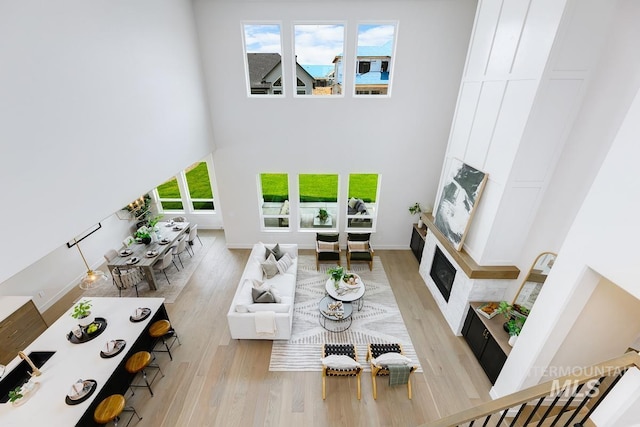 living room with a high ceiling, a wealth of natural light, and light hardwood / wood-style flooring