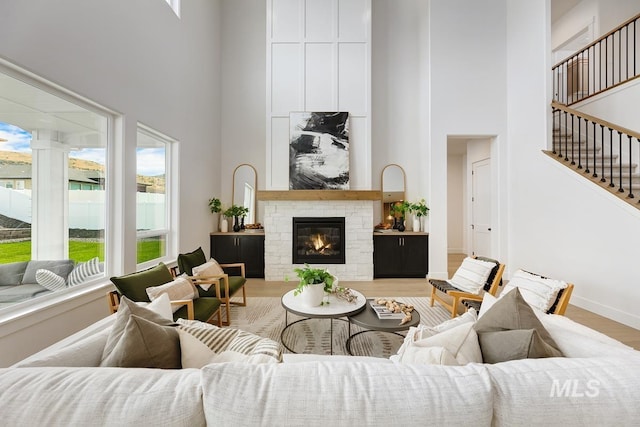 living room featuring plenty of natural light, a towering ceiling, and light hardwood / wood-style floors