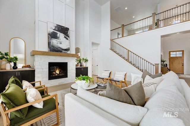 living room with a towering ceiling, wood-type flooring, and a stone fireplace