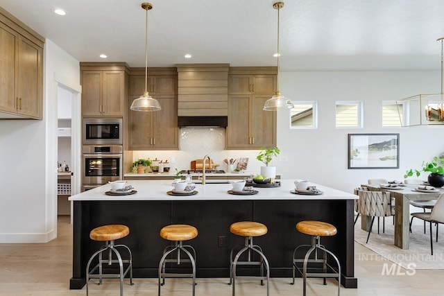 kitchen with a kitchen breakfast bar, an island with sink, stainless steel oven, and built in microwave