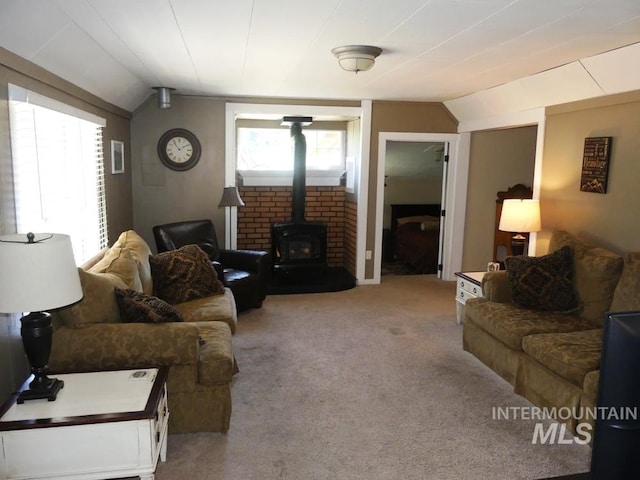 carpeted living room with a wood stove and vaulted ceiling