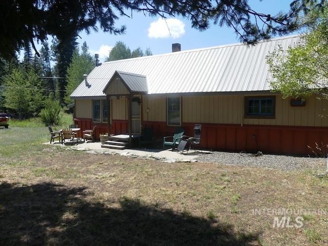 view of front facade with a patio area, metal roof, and a chimney