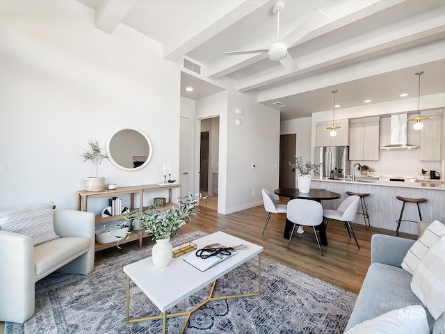 living room featuring ceiling fan, sink, dark hardwood / wood-style floors, and beamed ceiling