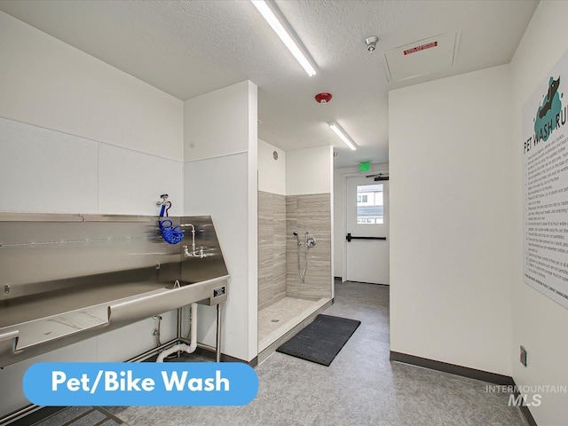 bathroom with a textured ceiling and a tile shower