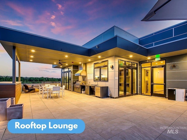 patio terrace at dusk featuring an outdoor kitchen and sink