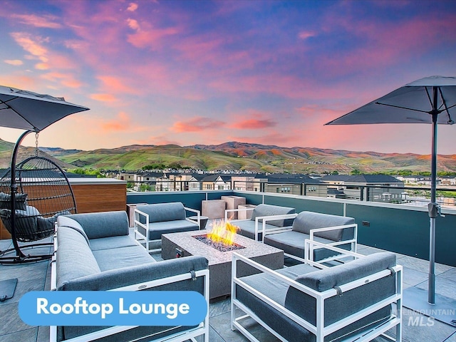 patio terrace at dusk featuring an outdoor living space with a fire pit and a mountain view