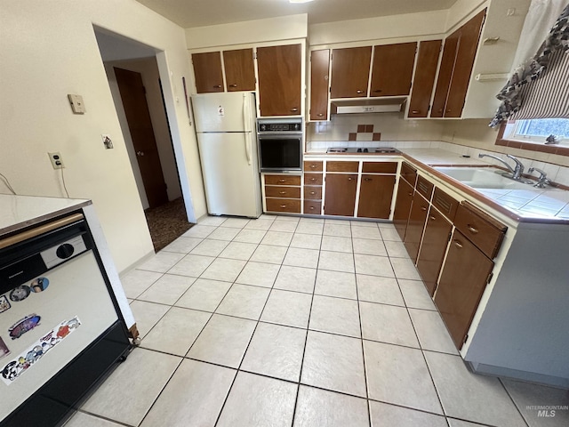 kitchen featuring tile countertops, light tile patterned flooring, white appliances, and sink