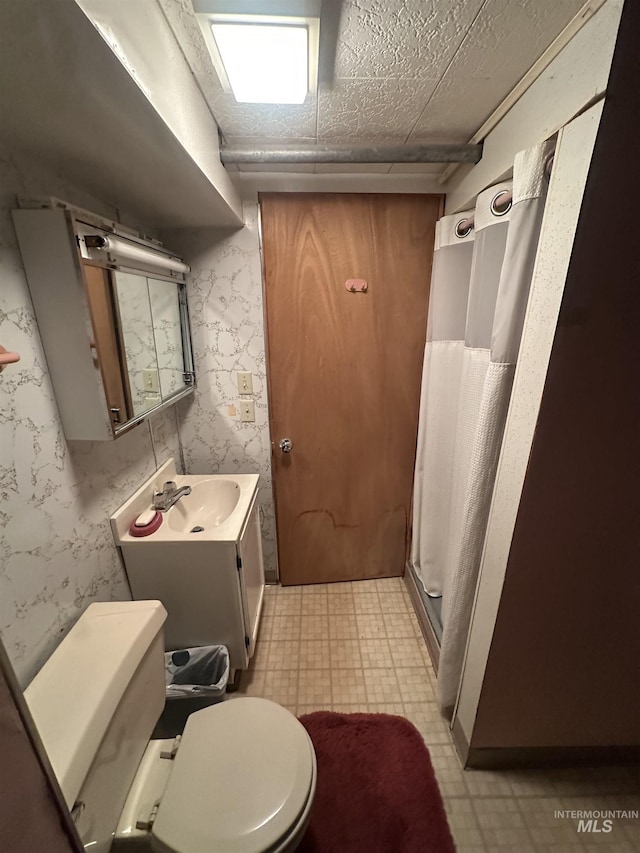 bathroom featuring a shower with shower curtain, vanity, toilet, and a textured ceiling