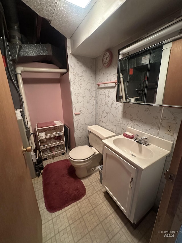 bathroom with a textured ceiling, vanity, and toilet