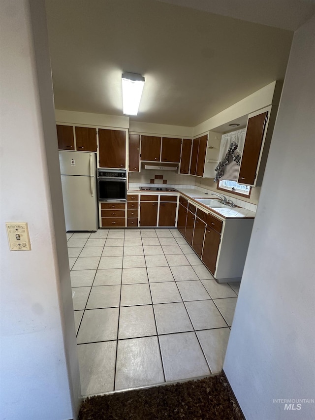 kitchen featuring black oven, white fridge, dark brown cabinets, and light tile patterned floors