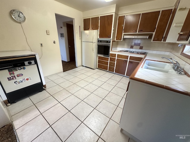 kitchen featuring black appliances, dark brown cabinets, sink, and tile countertops