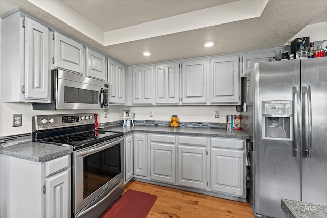 kitchen featuring recessed lighting, dark countertops, appliances with stainless steel finishes, and light wood finished floors