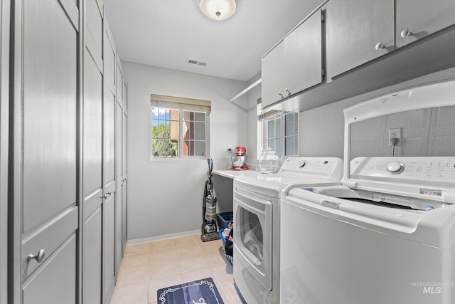 laundry area with visible vents, cabinet space, light tile patterned floors, baseboards, and washer and dryer