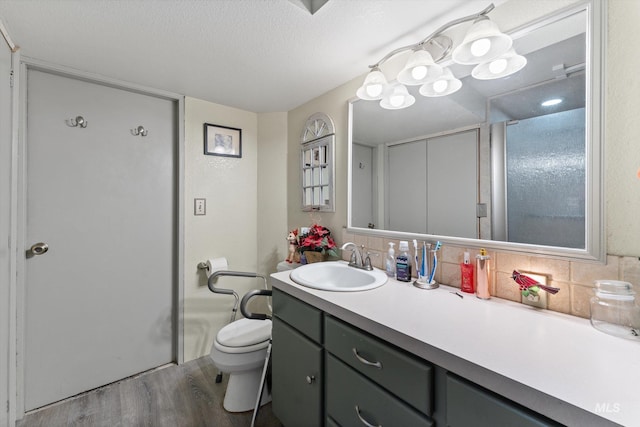 bathroom featuring vanity, decorative backsplash, wood finished floors, and toilet