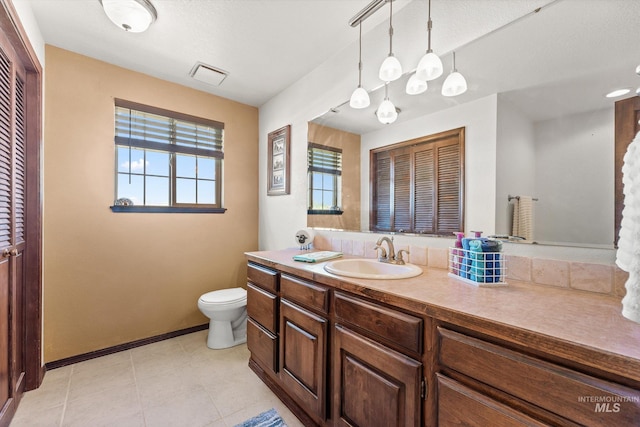 bathroom featuring vanity, baseboards, visible vents, and toilet