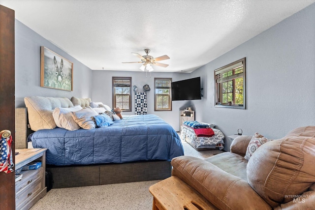 bedroom with light carpet, a ceiling fan, and a textured ceiling