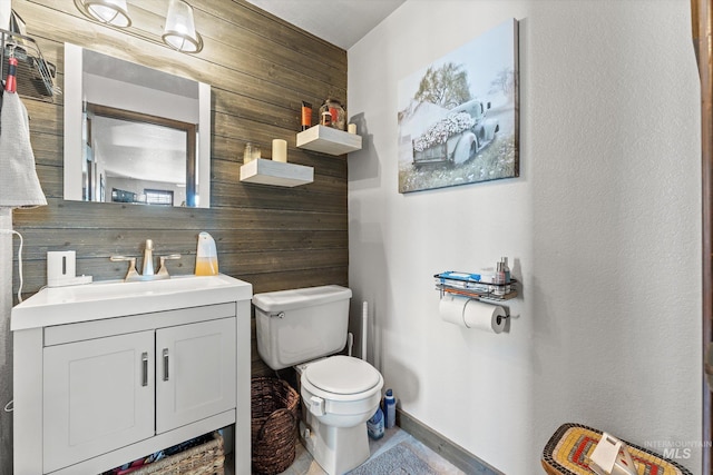 bathroom with vanity, baseboards, toilet, and wood walls