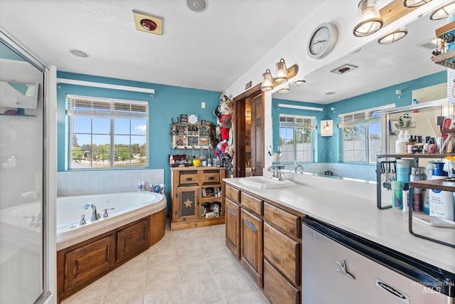 full bath with vanity, plenty of natural light, a garden tub, and tile patterned floors