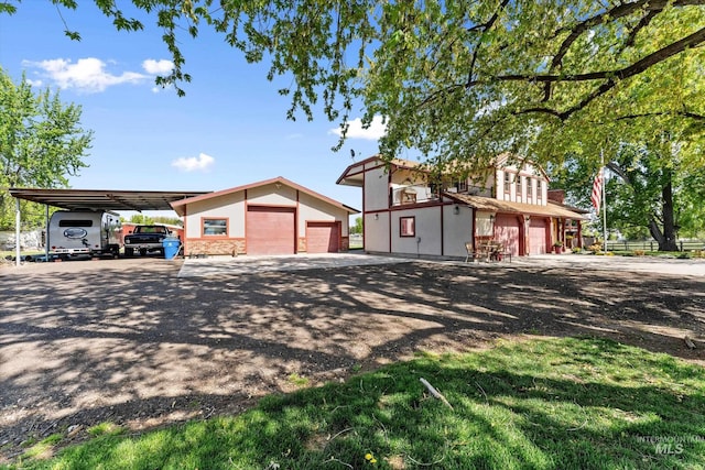 view of front of home with dirt driveway and a garage