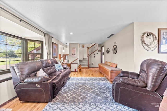 living room featuring visible vents, stairs, and wood finished floors