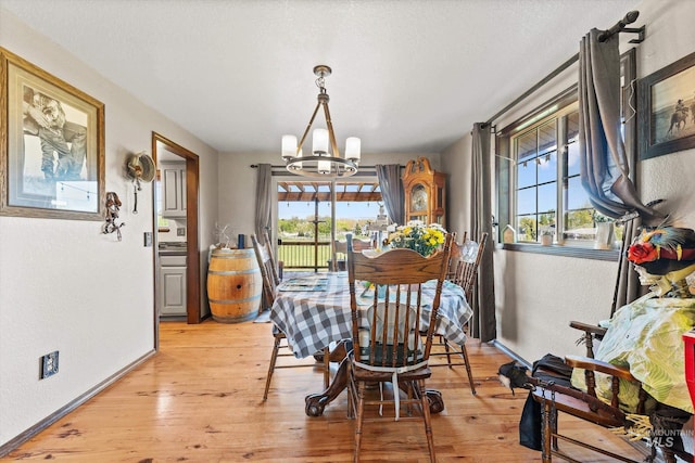 dining area featuring an inviting chandelier, plenty of natural light, and light wood-style flooring
