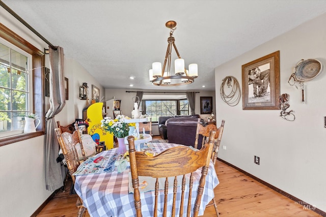 dining area featuring baseboards, light wood finished floors, and a chandelier