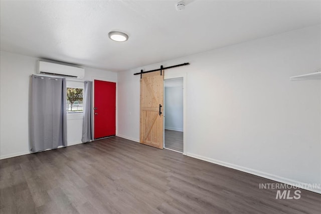 216 9th Ave N, Nampa, ID 83687 - unfurnished bedroom featuring a wall mounted air conditioner, wood finished floors, a barn door, and baseboards