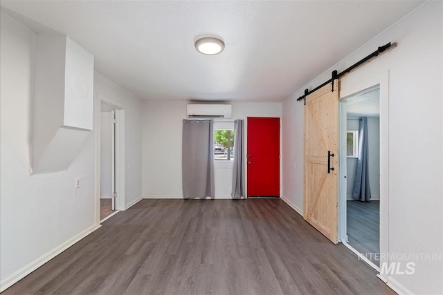 216 9th Ave N, Nampa, ID 83687 - unfurnished room with a barn door, an AC wall unit, dark wood-style flooring, and baseboards
