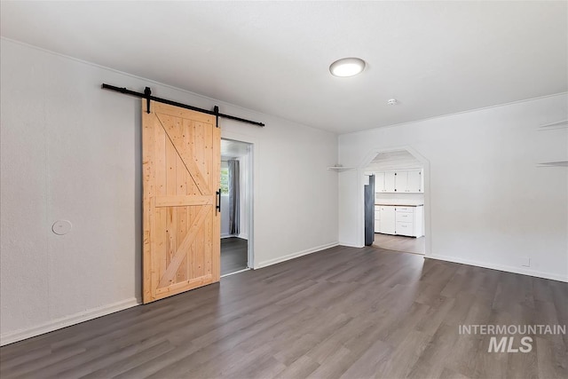 216 9th Ave N, Nampa, ID 83687 - spare room with dark wood-style floors, a barn door, baseboards, and arched walkways
