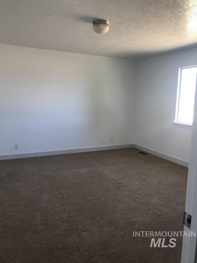 carpeted empty room featuring a textured ceiling