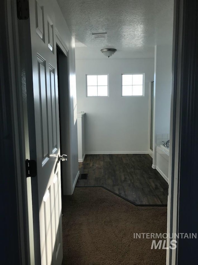 hall with dark hardwood / wood-style flooring and a textured ceiling