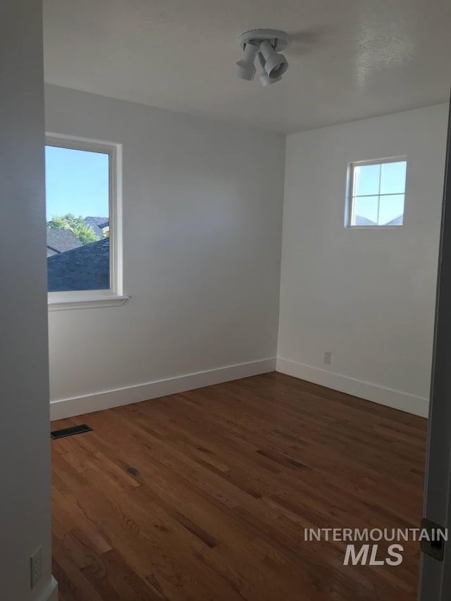 spare room with plenty of natural light and dark wood-type flooring