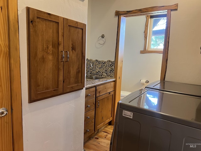 laundry room featuring light wood-type flooring, cabinets, and sink