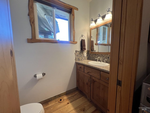 bathroom with toilet, vanity, backsplash, and wood-type flooring