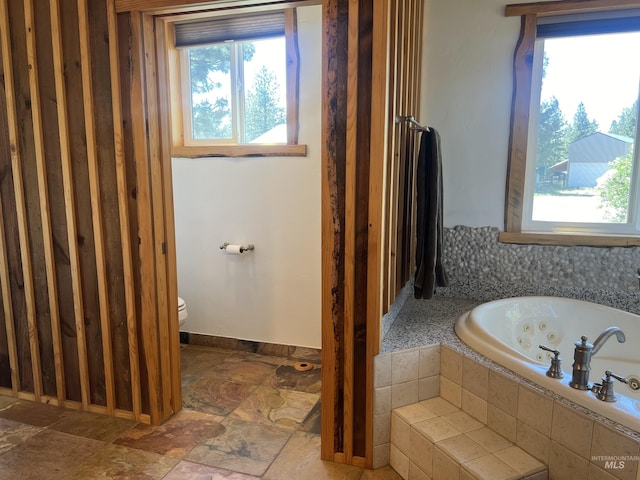 bathroom featuring toilet and tiled tub