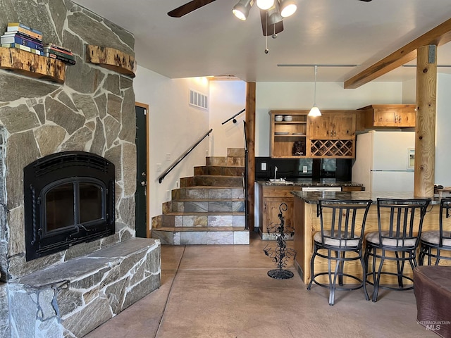 kitchen featuring ceiling fan, sink, concrete flooring, white refrigerator with ice dispenser, and beamed ceiling