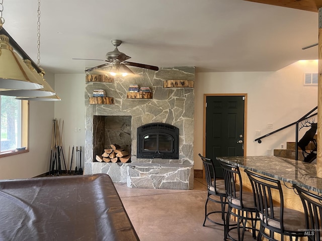 living room featuring ceiling fan and a stone fireplace