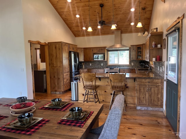 kitchen featuring kitchen peninsula, stainless steel appliances, tasteful backsplash, decorative light fixtures, and sink